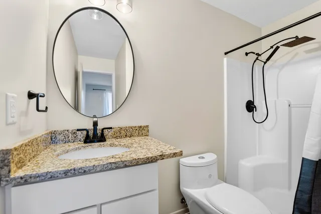 a bathroom with a granite countertop sink toilet and a mirror