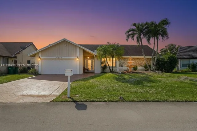 front view of house with a yard and palm trees