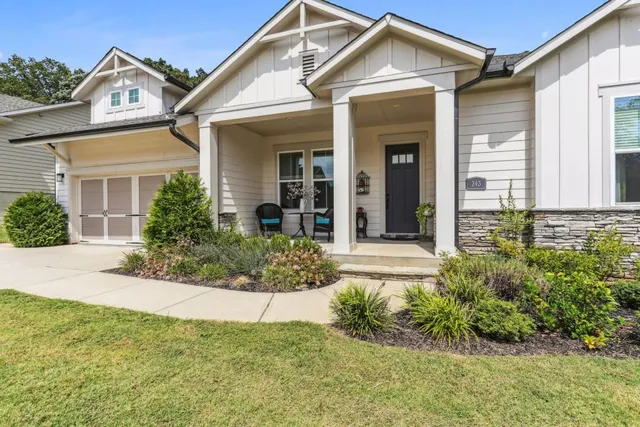 a view of a house with small yard plants and large tree