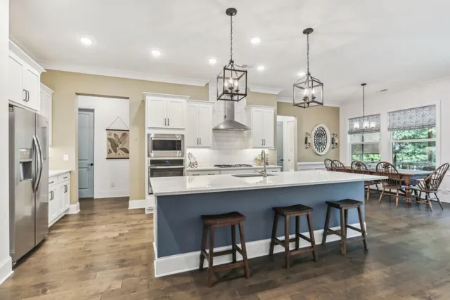 a kitchen with stainless steel appliances granite countertop a kitchen island a stove and a view of living room