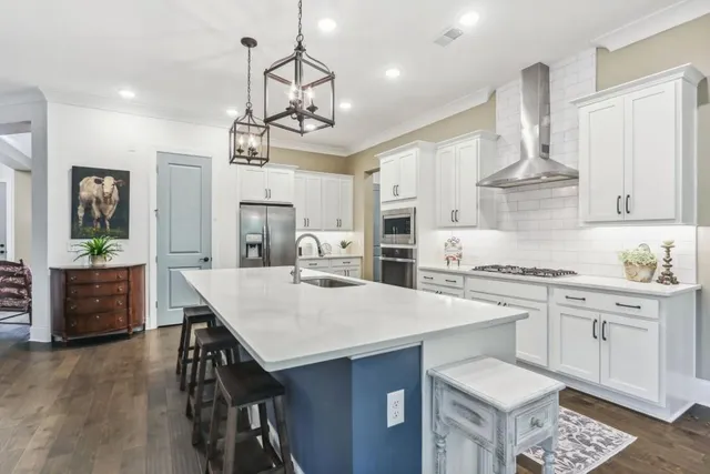 a kitchen with stainless steel appliances a stove a sink dishwasher a stove a dining table and chairs with wooden floor