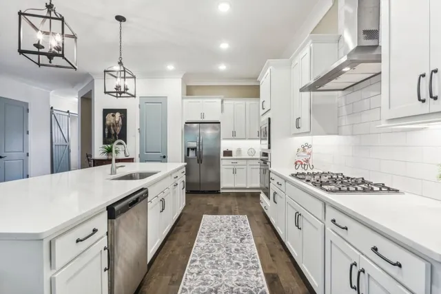 a large kitchen with stainless steel appliances kitchen island granite countertop a stove a sink dishwasher and a refrigerator with wooden floor