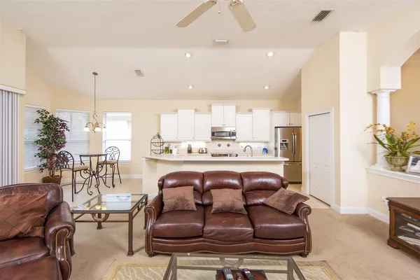 a living room with stainless steel appliances furniture and a kitchen view