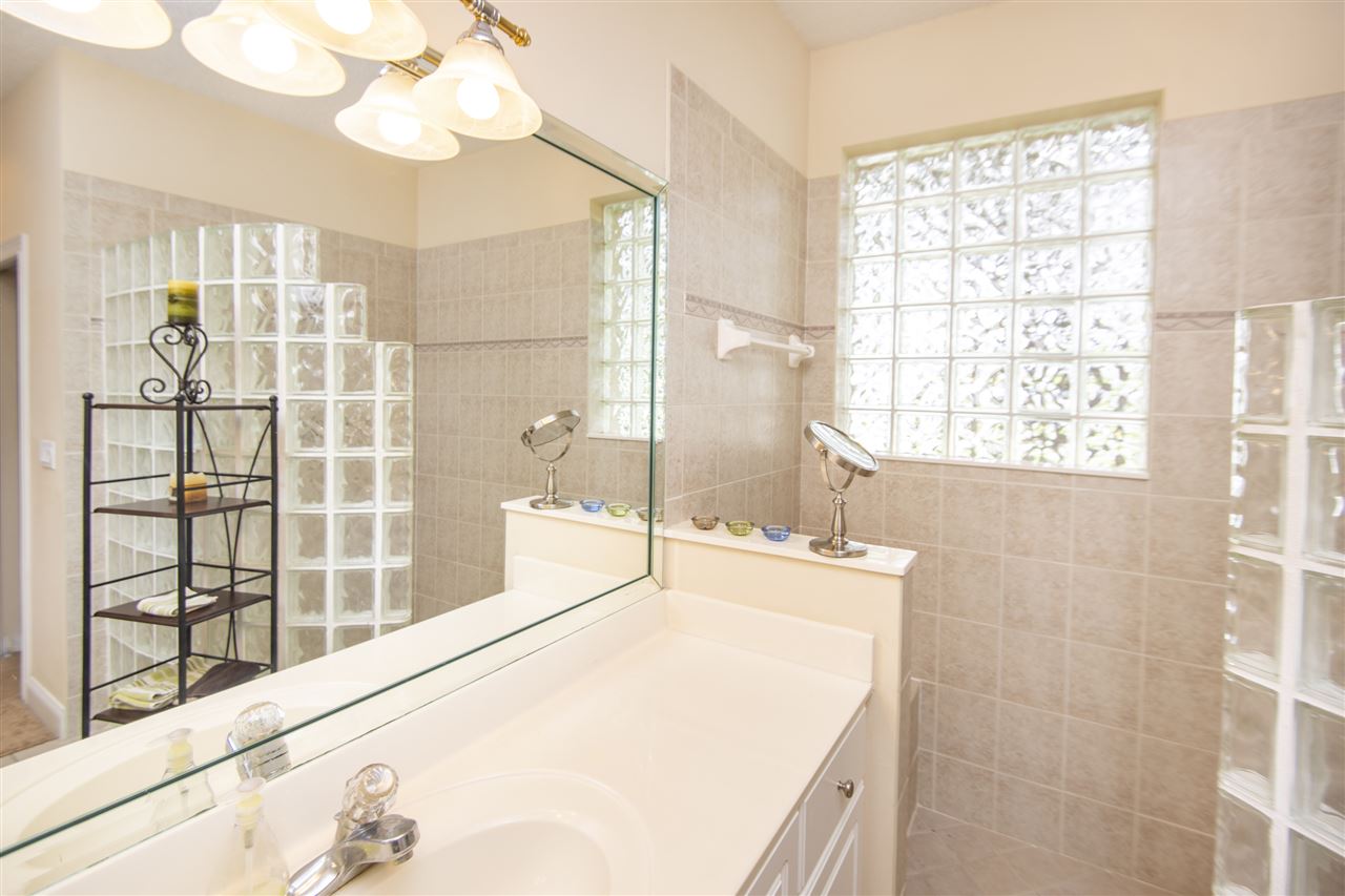 128 St Andrews Pl Drive St. Augustine, FL 32092 - Photo 26 of 38 a spacious bathroom with a granite countertop sink a large mirror and shower