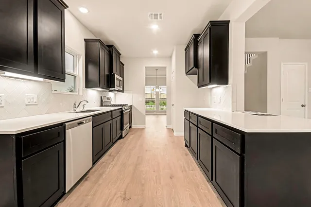 a large kitchen with a large counter top sink and stainless steel appliances