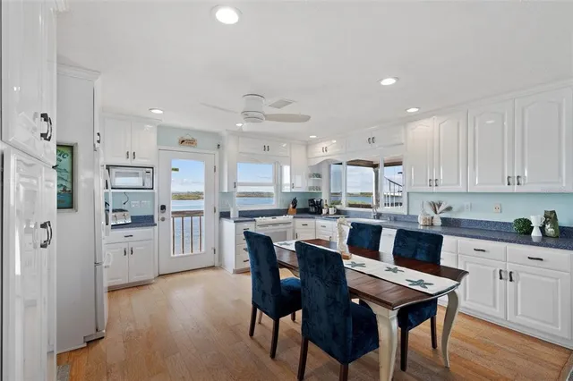 a kitchen with stainless steel appliances kitchen island granite countertop a table chairs and a refrigerator