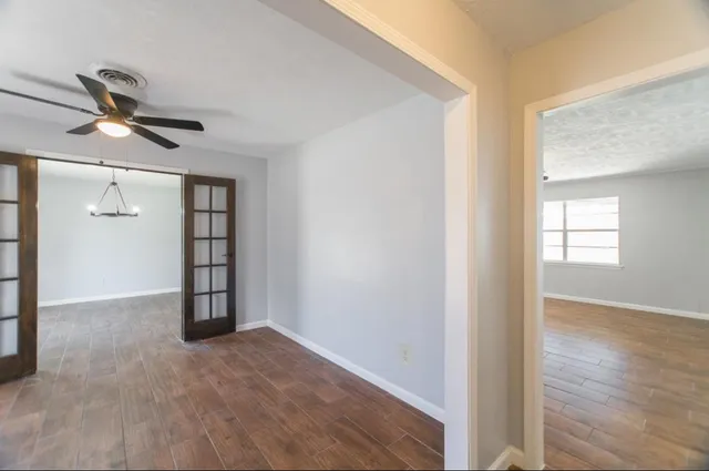 an empty room with wooden floor cabinet and windows