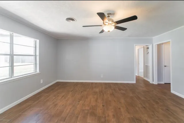 a view of an empty room with wooden floor and a window