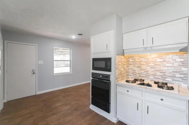 a kitchen with granite countertop white cabinets and appliances