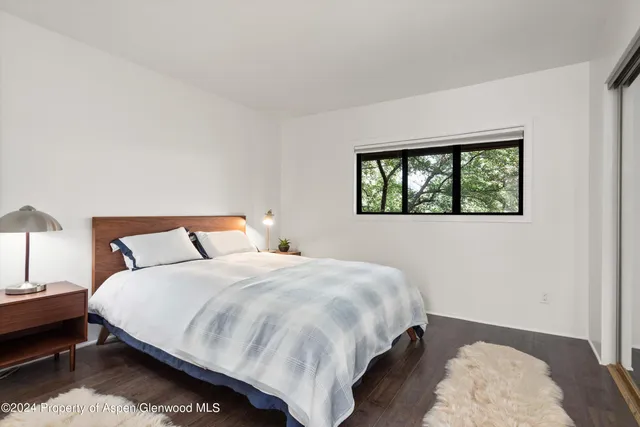 a bedroom with a bed wooden floor and window