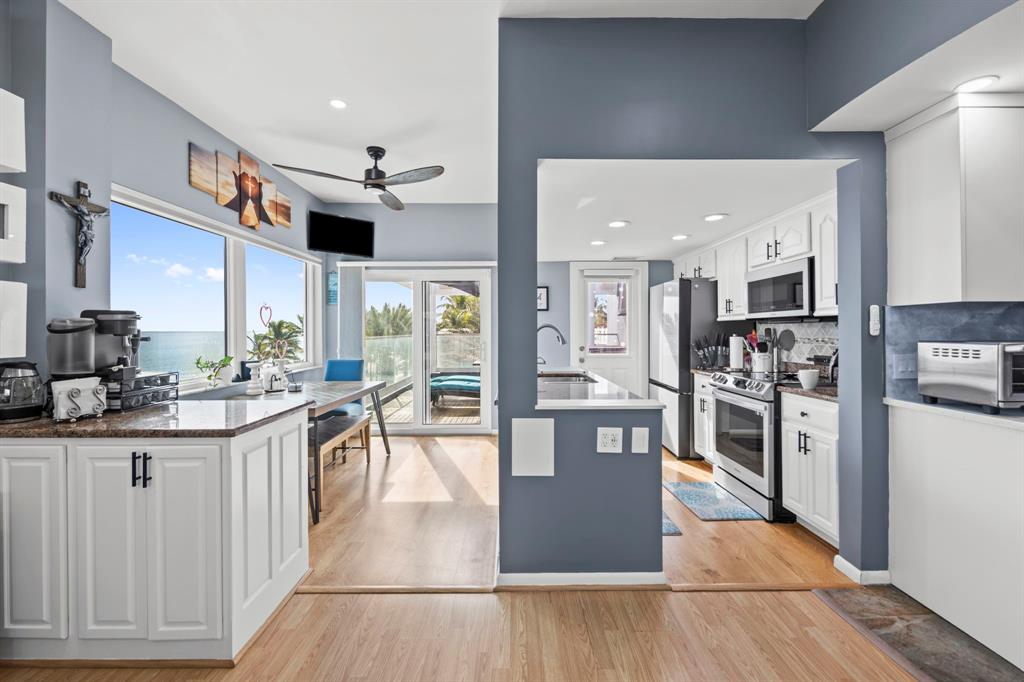 2203 North Surf Road Hollywood, FL 33019 - Photo 22 of 60 a kitchen with stainless steel appliances granite countertop a stove top oven a sink a dining table and chairs with wooden floor
