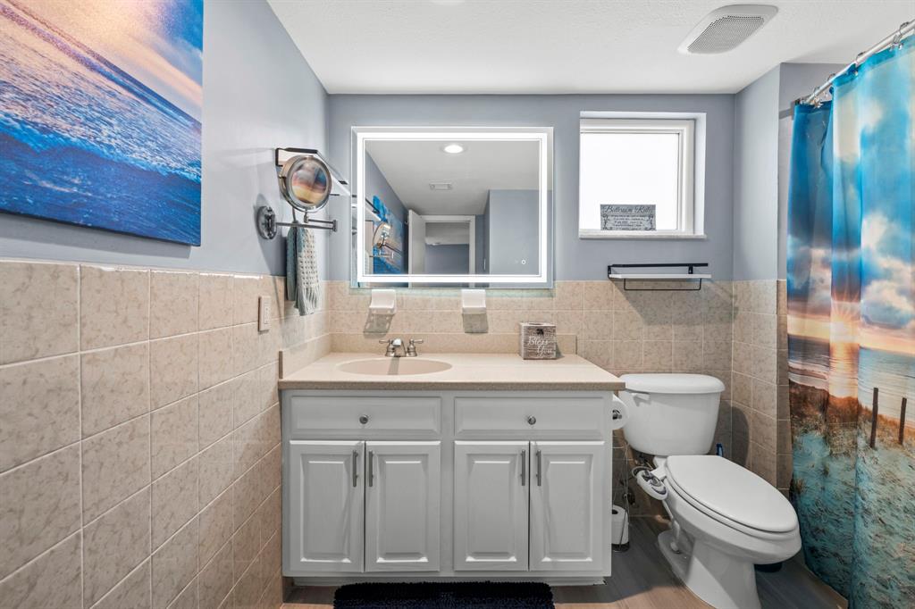 2203 North Surf Road Hollywood, FL 33019 - Photo 48 of 60 a bathroom with a toilet a sink a mirror a window and vanity