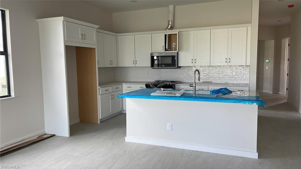 14557 Kingfisher Loop Naples, FL 34120 - Photo 3 of 27 a kitchen with stainless steel appliances a stove a refrigerator a sink a microwave and cabinets