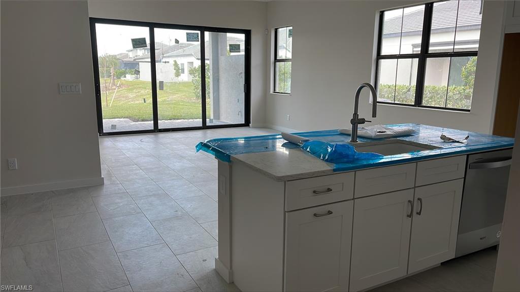 14557 Kingfisher Loop Naples, FL 34120 - Photo 6 of 27 a kitchen with a granite countertop sink and natural light