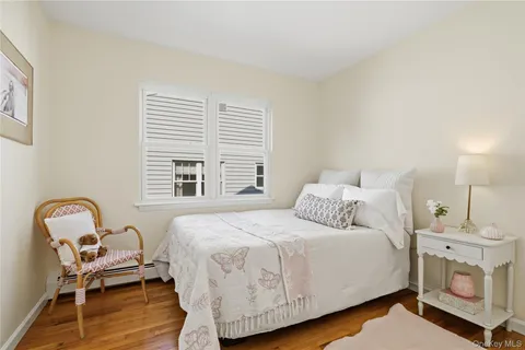 a bedroom with a bed a couch and wooden floor