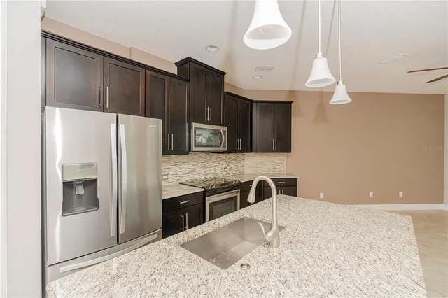 a kitchen with stainless steel appliances granite countertop a refrigerator a stove and a sink with wooden floor