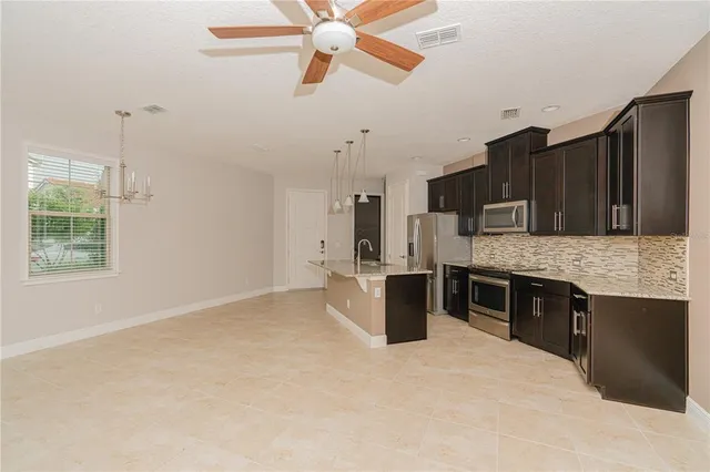 a kitchen with stainless steel appliances kitchen island granite countertop a stove a sink dishwasher and a refrigerator