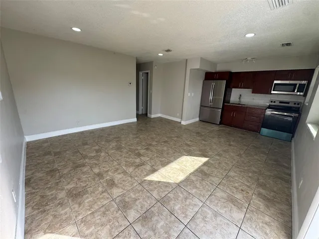 a kitchen with granite countertop a refrigerator and a stove top oven