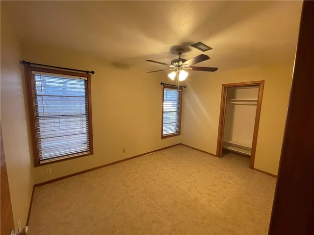 an empty room with windows and fan