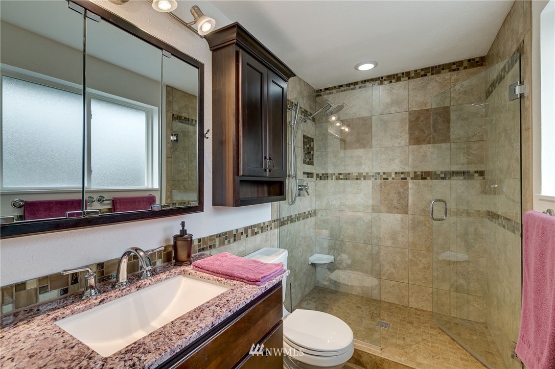 519 213th Place Southwest Bothell, WA 98021 - Photo 12 of 34 a bathroom with a granite countertop sink a toilet a mirror and shower