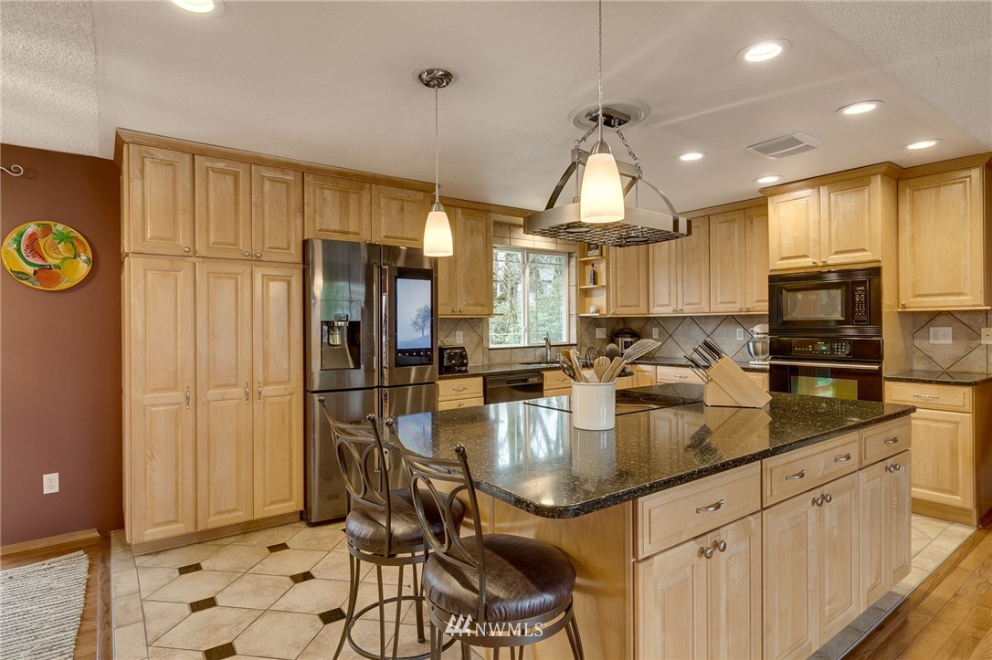 519 213th Place Southwest Bothell, WA 98021 - Photo 7 of 34 a kitchen with stainless steel appliances granite countertop a refrigerator a sink a stove and white cabinets with wooden floor