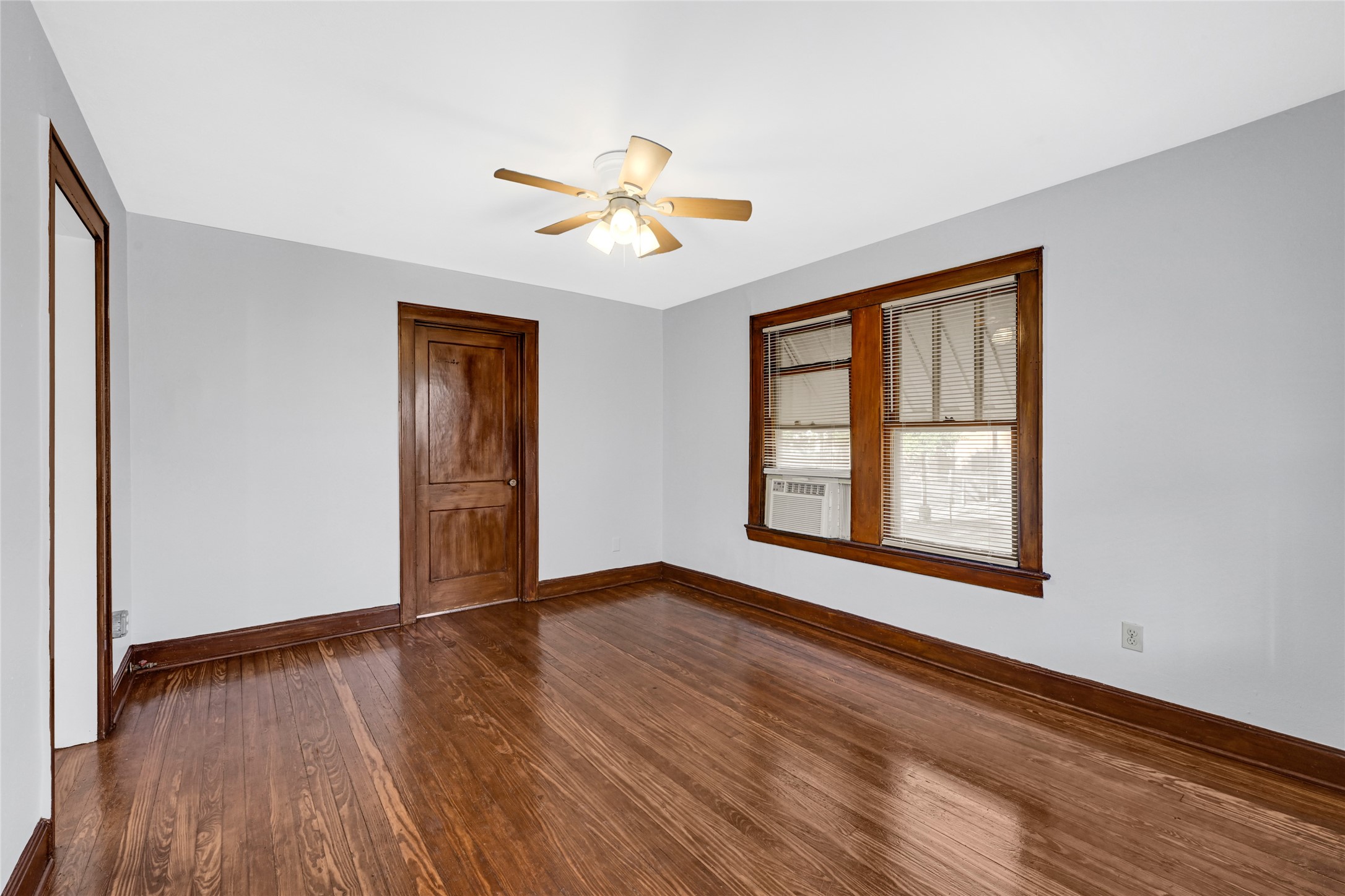 a view of an empty room with window and wooden floor