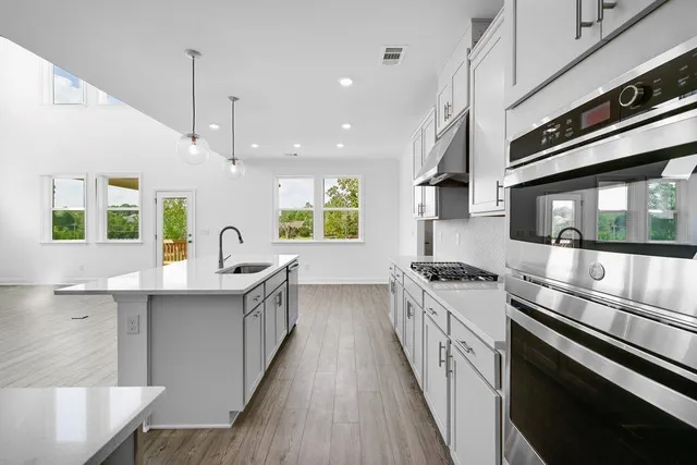an open kitchen with wooden floor and stainless steel appliances