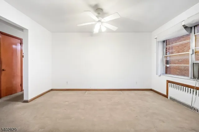 an empty room with a window and a ceiling fan