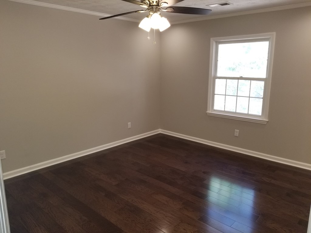 10089 County Line Road Midland, GA 31820 - Photo 21 of 27 an empty room with wooden floor windows and fan