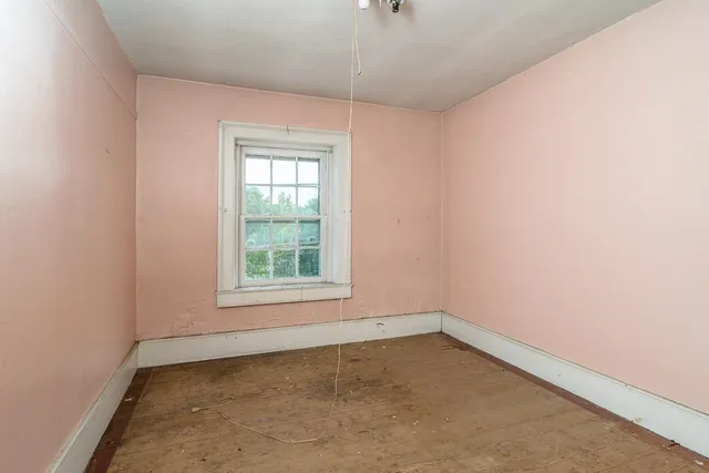 an empty room with a fireplace and windows