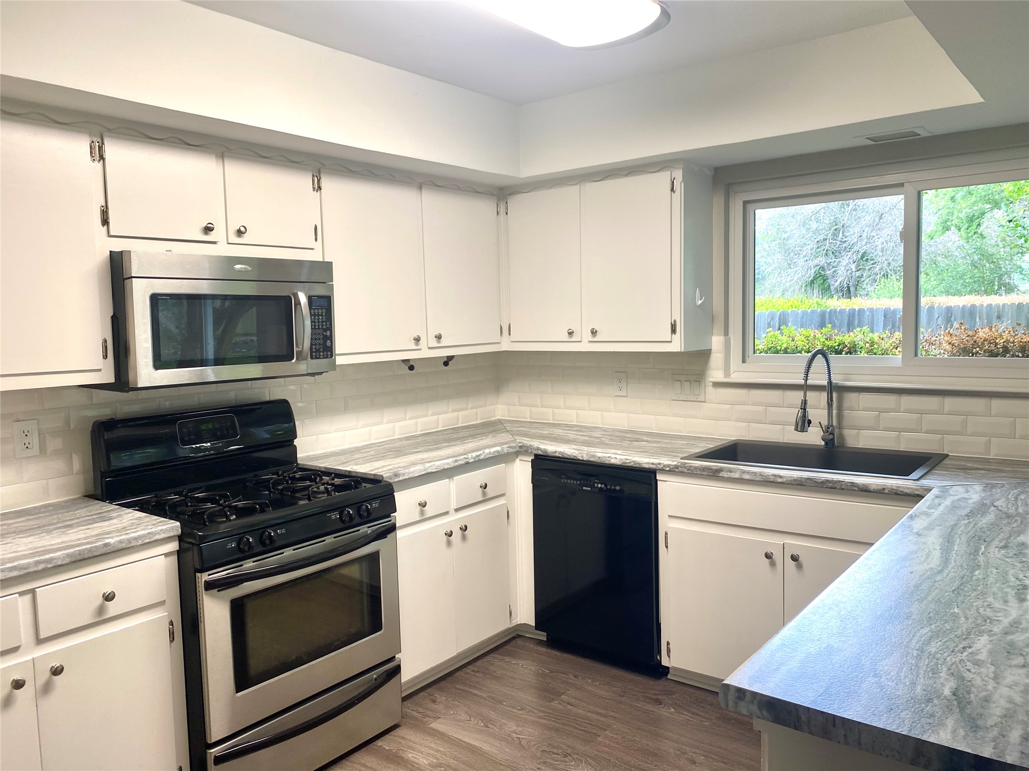 11505 Windermere Meadows Austin, TX 78759 - Photo 5 of 16 a kitchen with granite countertop a stove a sink and a microwave