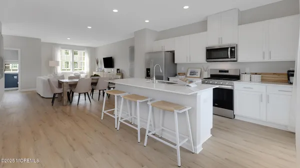 a large kitchen with cabinets chairs and wooden floor