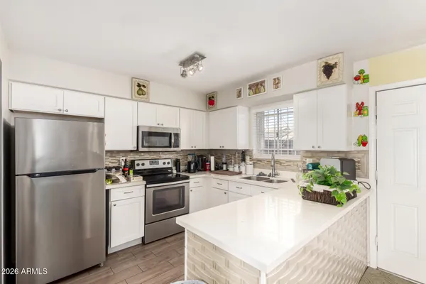 a kitchen with a refrigerator a stove a sink and white cabinets