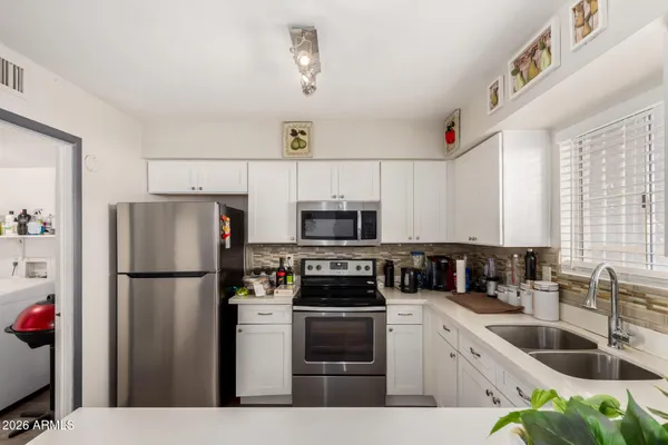 a kitchen with a refrigerator a stove a sink a counter space and cabinets