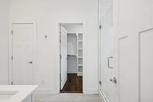a view of a hallway with wooden floor and closet area