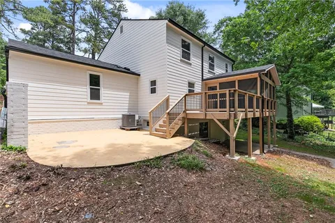 a view of a house with a yard and large trees