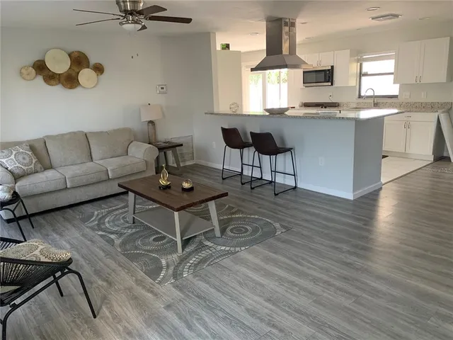 a kitchen with stainless steel appliances kitchen island granite countertop a table chairs in it and wooden floors