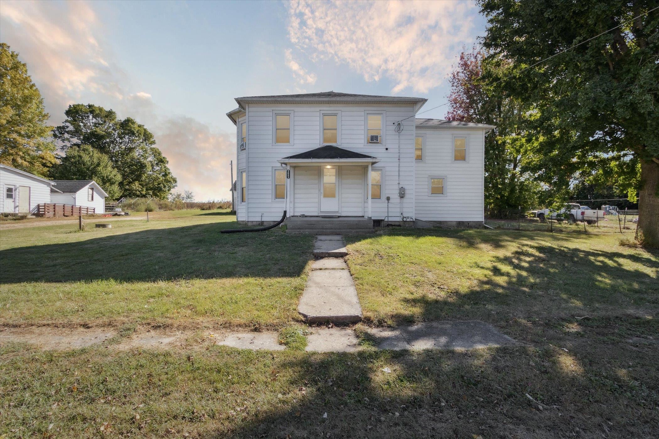 a view of a white house with a yard and large tree