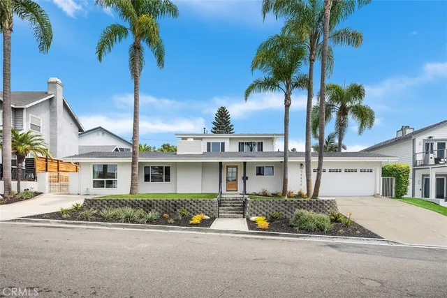 front view of a house with a yard and palm trees