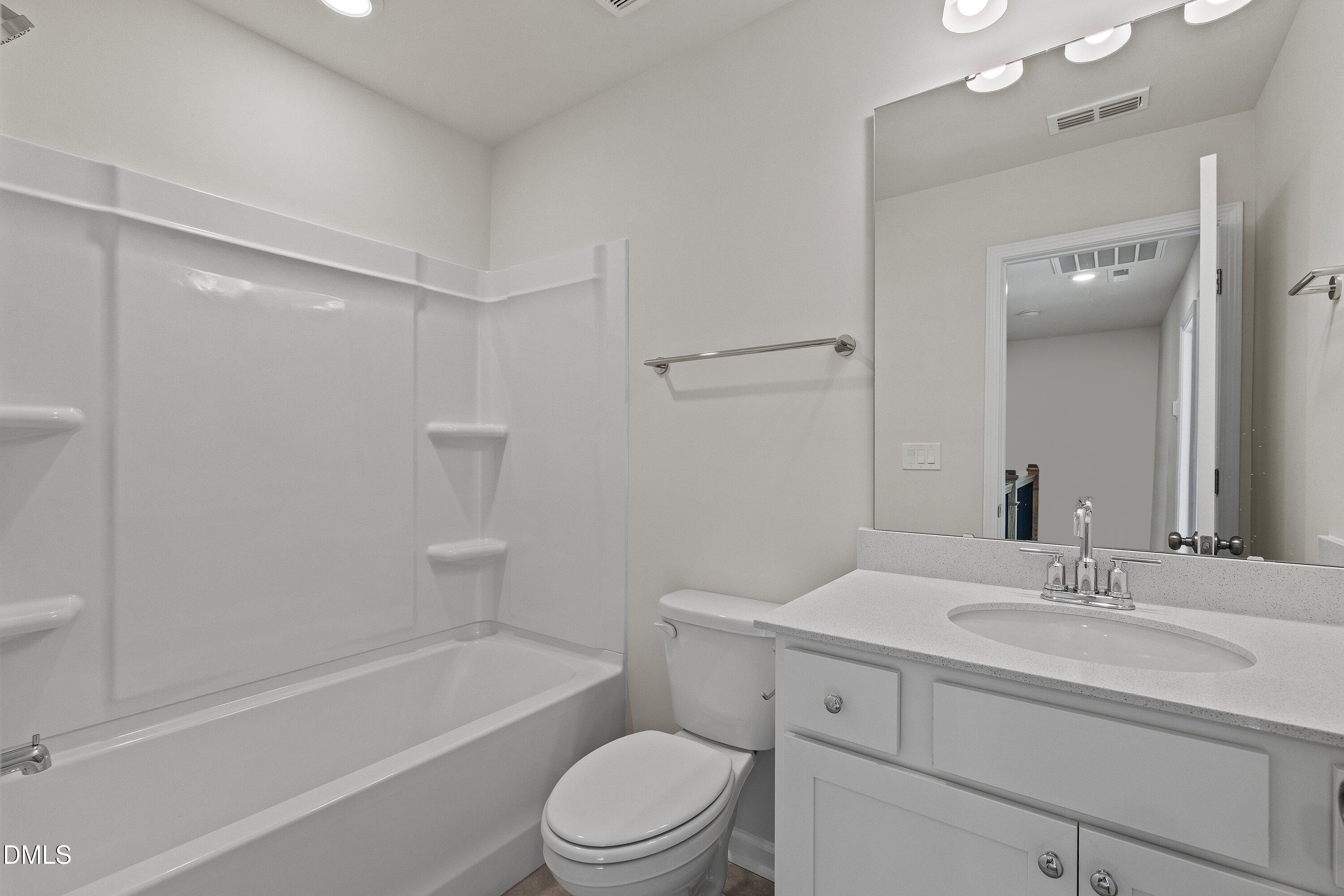 7242 Morris Acres Road Apex, NC 27523 - Photo 30 of 35 a bathroom with a toilet a sink a mirror a bathtub and vanity