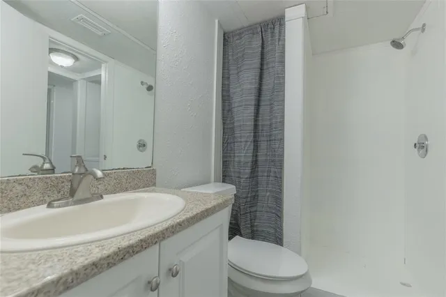 a bathroom with a granite countertop sink toilet and shower