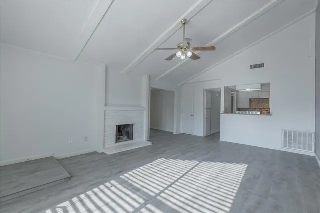 a view of a livingroom with a fireplace a chandelier fan and windows