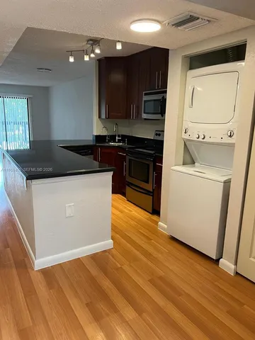 a kitchen with stainless steel appliances granite countertop a stove top oven a sink and a refrigerator