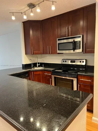 a kitchen with kitchen island granite countertop stainless steel appliances and wooden cabinets