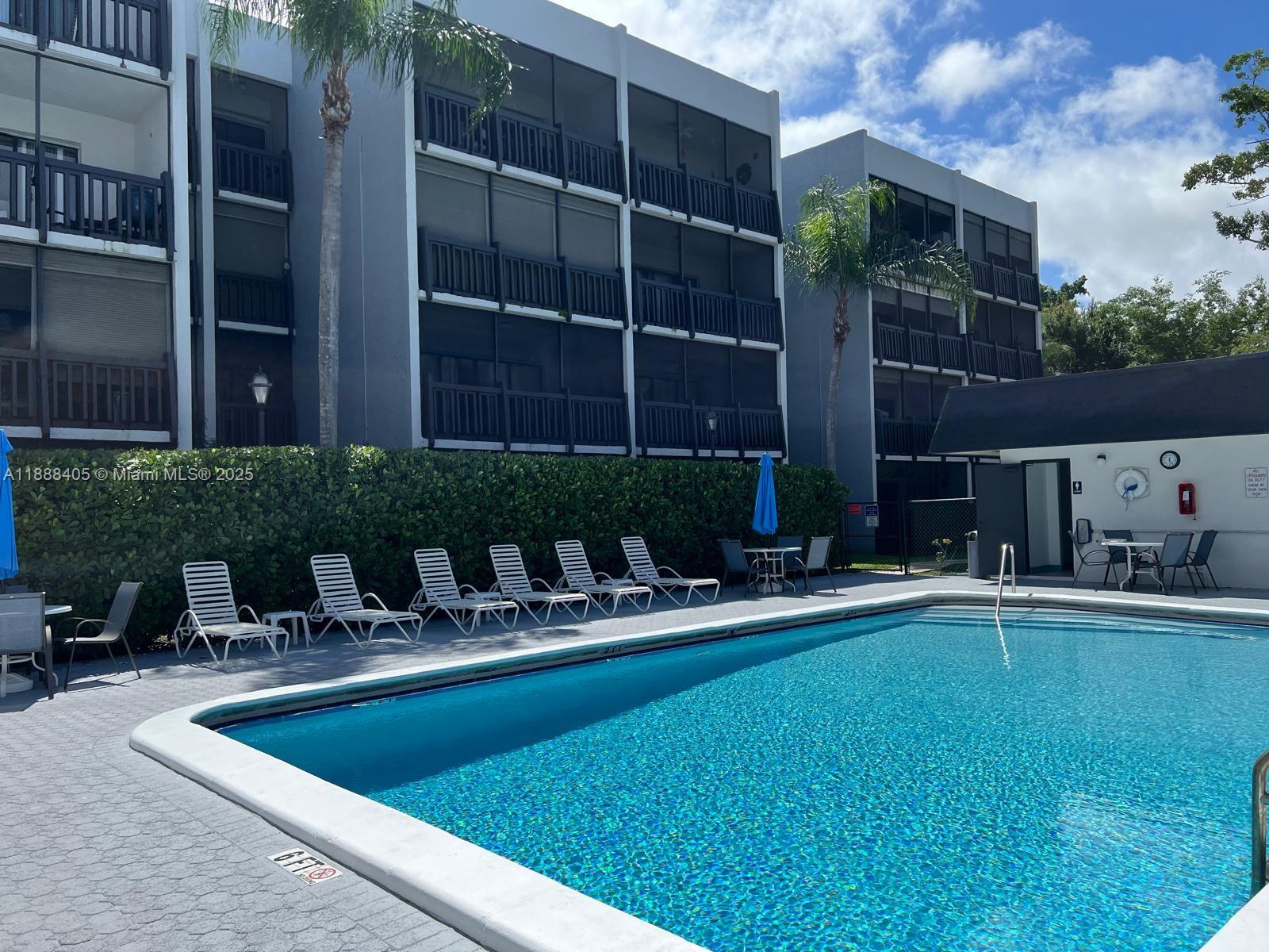 1021 Mockingbird Lane, Unit 209 Plantation, FL 33324 - Photo 23 of 26 a view of pool with lawn chairs and plants