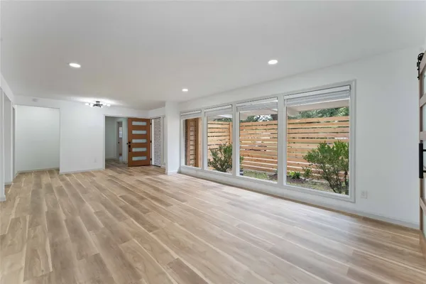 a view of an empty room with a window and wooden floor