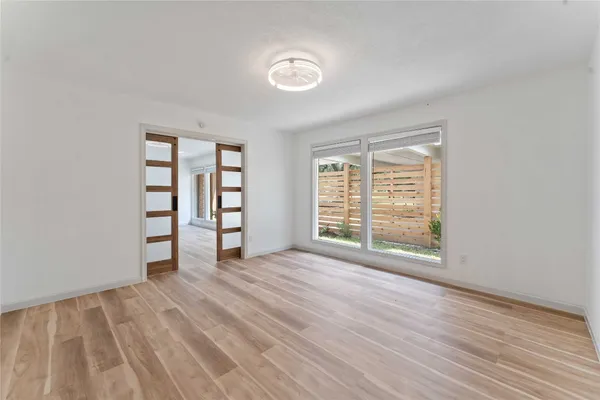 a view of an empty room with a window and wooden floor