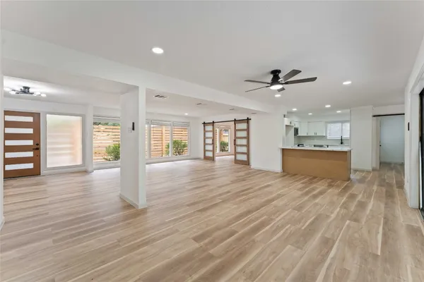 a view of an empty room with a kitchen and wooden floor