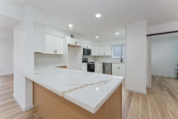 a kitchen with a sink a stove a refrigerator and white cabinets