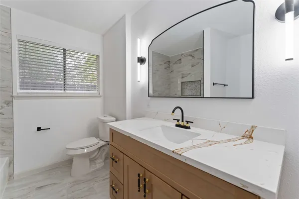 a bathroom with a sink vanity mirror and toilet